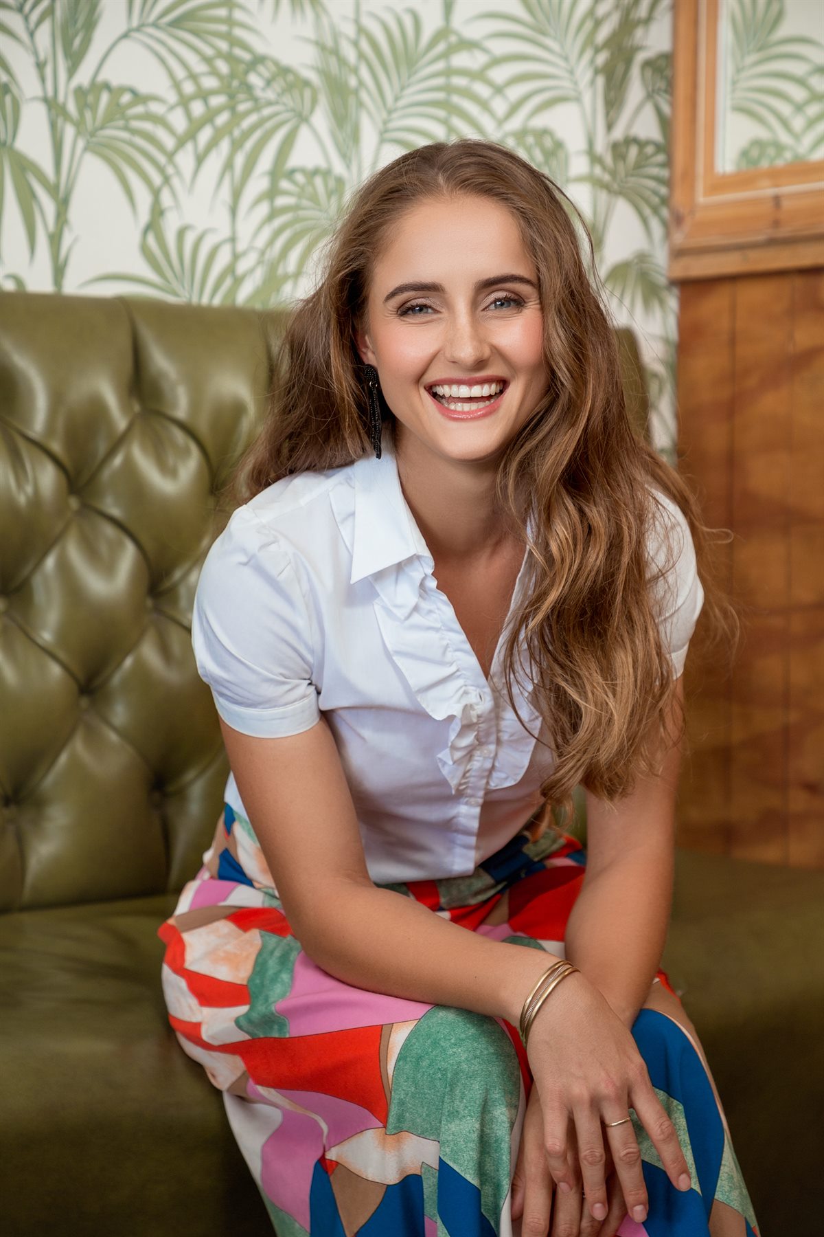 Dr Carlien Neethling laughing, seated on a green leather couch